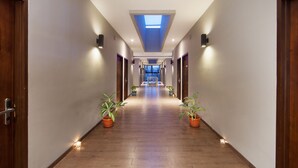 A long, well-lit hallway with wooden floors, potted plants, and a skylight at the end. - D'River Guesthouse (Bandung)