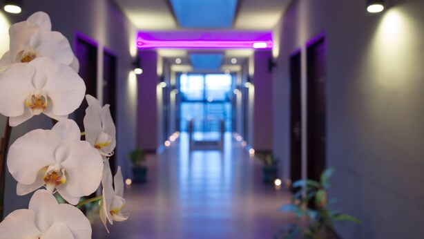 A hotel hallway with a modern design, featuring a central lighted pathway and a ceiling with a blue light feature. - D'River Guesthouse (Bandung)