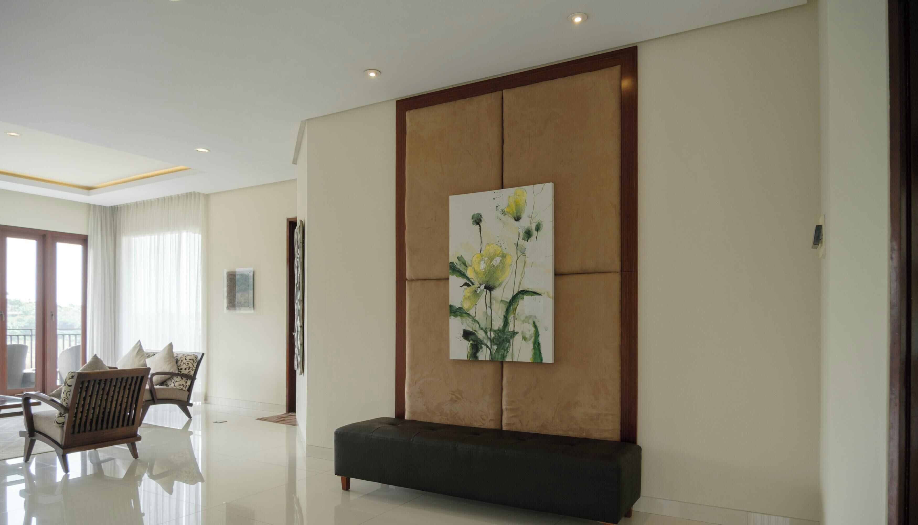 A modern interior with a large painting, a dark bench, and a seating area with chairs.