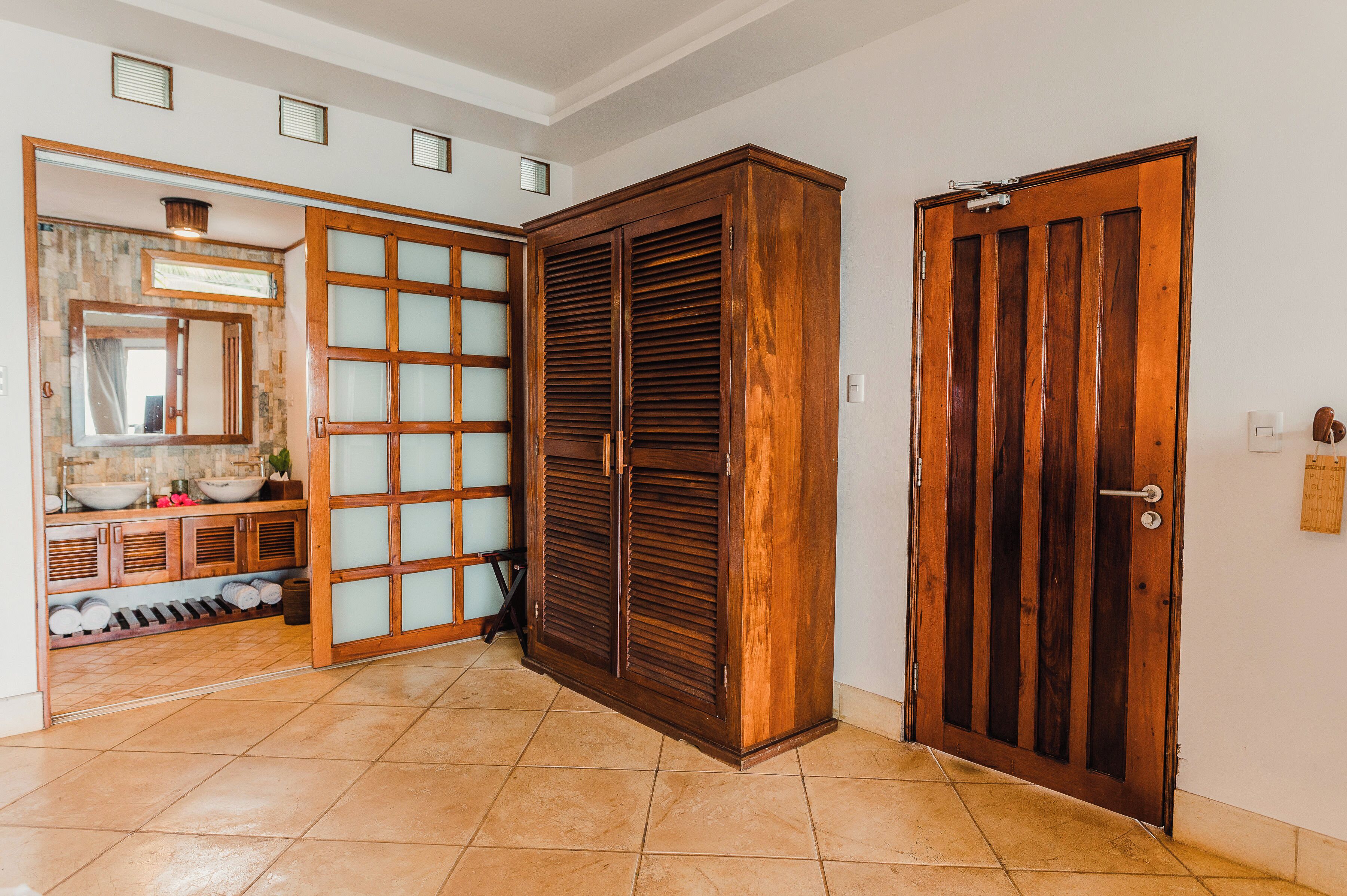 Une pièce avec une armoire en bois, un miroir et un sol carrelé.