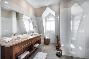 Un bagno moderno con un ampio specchio, due lavabi, un mobile vanitario in legno e un design di soffitto originale.