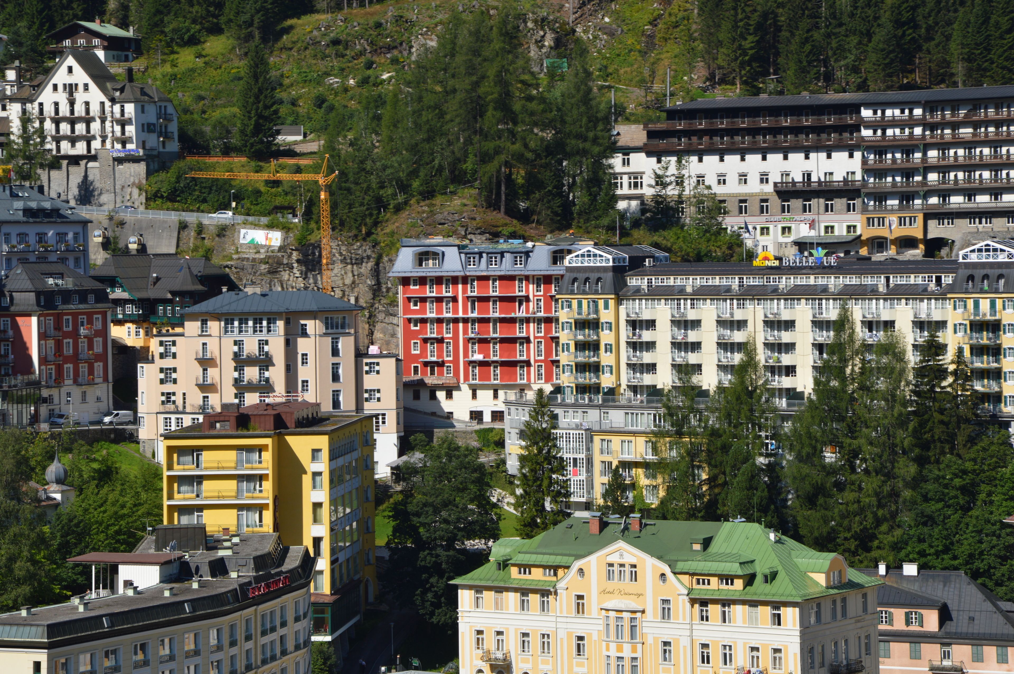 Un hôtel à plusieurs étages doté de balcons, d’un toit végétalisé et offrant une vue sur les bâtiments et les arbres environnants.