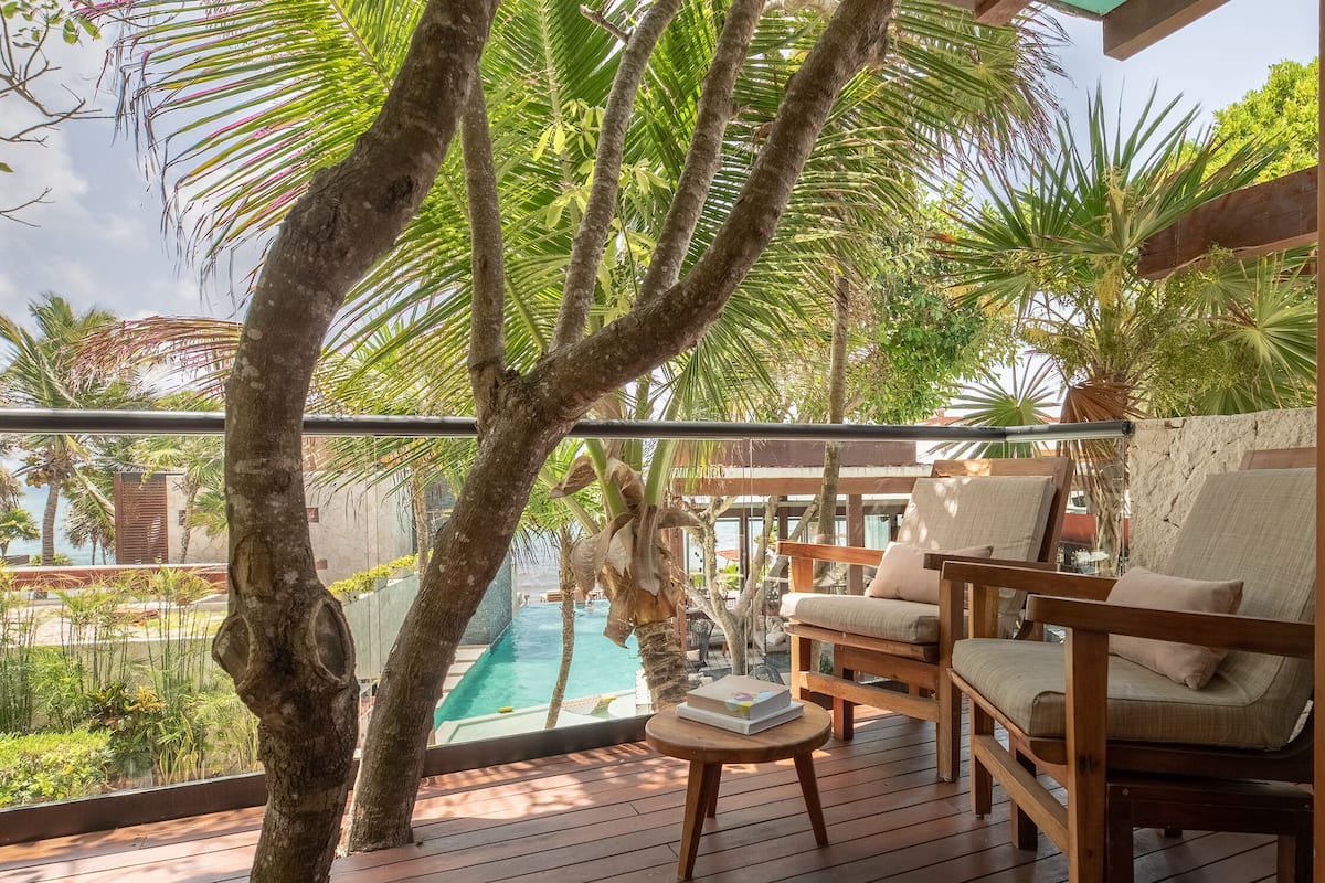 Eine Holzterrasse mit Pool, Palmen und Sitzgelegenheiten im Freien.