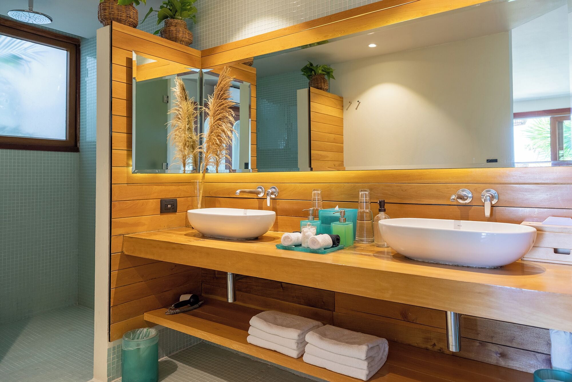 Une salle de bain avec deux lavabos, un miroir et des meubles en bois. On y trouve des serviettes et des articles de toilette sur le comptoir.