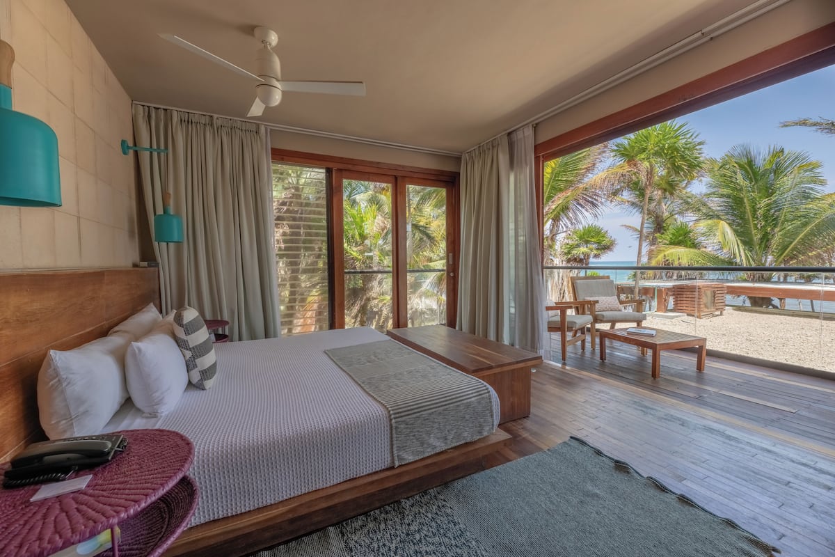 Ein Schlafzimmer mit Bett, Nachttisch und Blick auf den Strand.