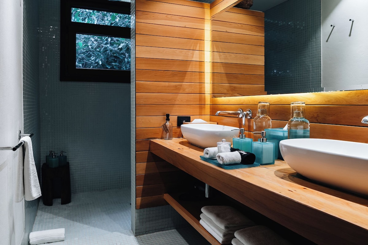 Un baño moderno con paneles de madera, dos lavamanos y un espejo grande.