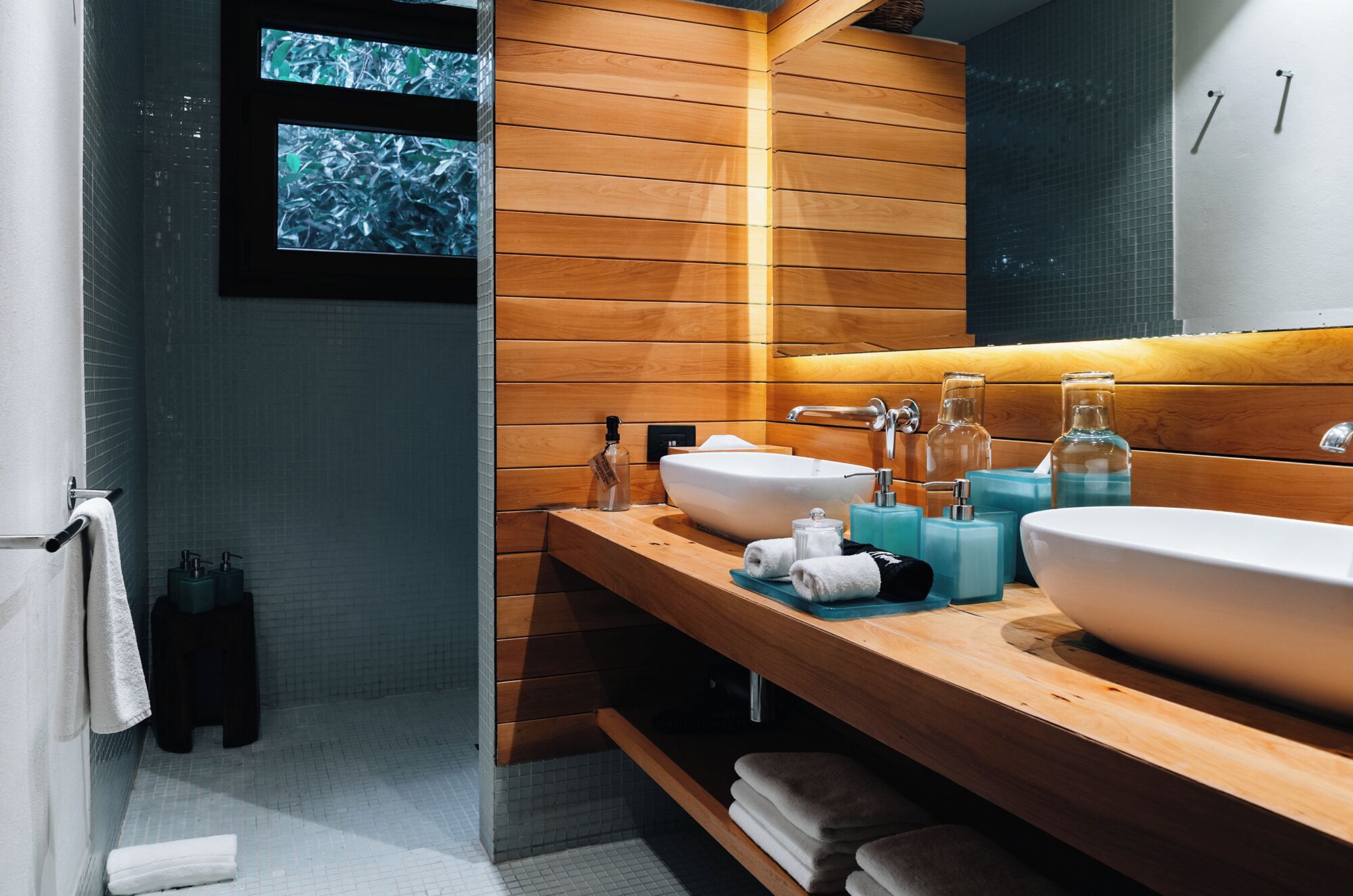 Une salle de bain moderne avec un lambris en bois, deux vasques et un grand miroir.