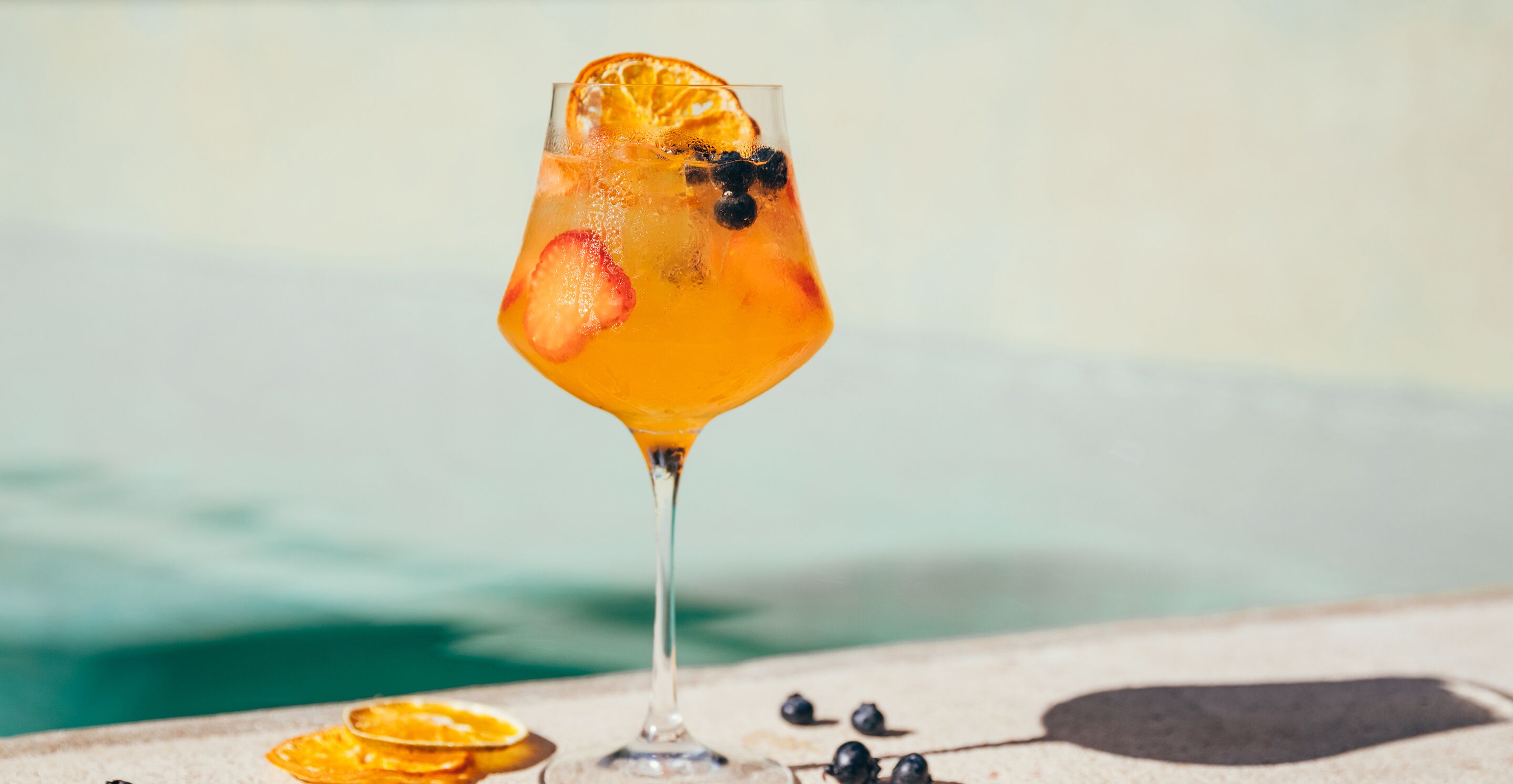 Ein Cocktailglas mit Obst auf einem Tisch in Poolnähe.