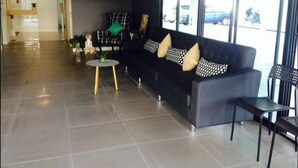 A modern lobby with a black sofa, a small round table, and a chair. - Vanilla Residence Chiangmai (Chiang Mai)
