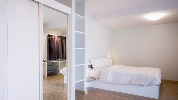 A bedroom with a bed, a wardrobe, and a built-in shelf unit. - Vanilla Residence Chiangmai (Chiang Mai)