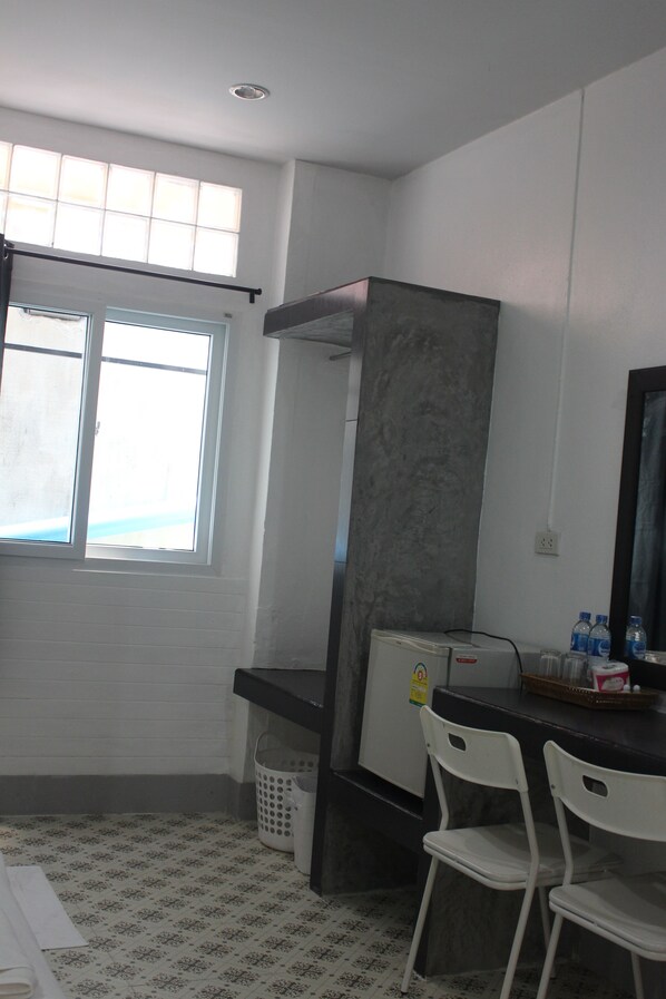 A small, clean room with a window, a sink, a mirror, and a chair.
