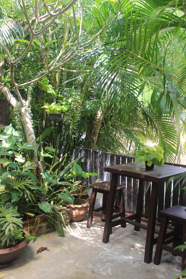 A patio area with a wooden table and chairs, surrounded by potted plants and a wooden fence.