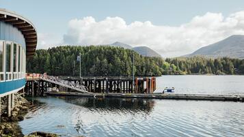 Un muelle se adentra en un lago tranquilo, con una montaña boscosa al fondo.