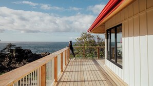 A wooden deck with a railing overlooking a rocky coastline and the sea.
