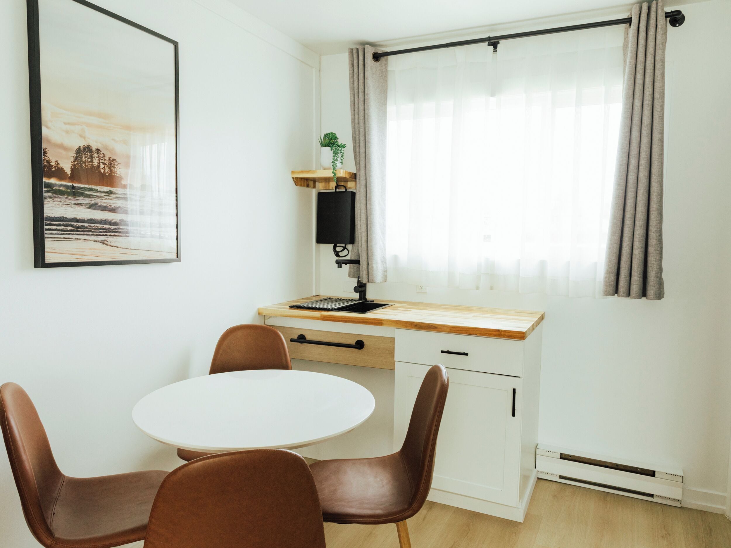 Una habitación pequeña y moderna con un escritorio de madera, una silla blanca y una mesita.