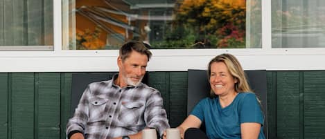 Two people sitting on a bench outside a building with large windows.