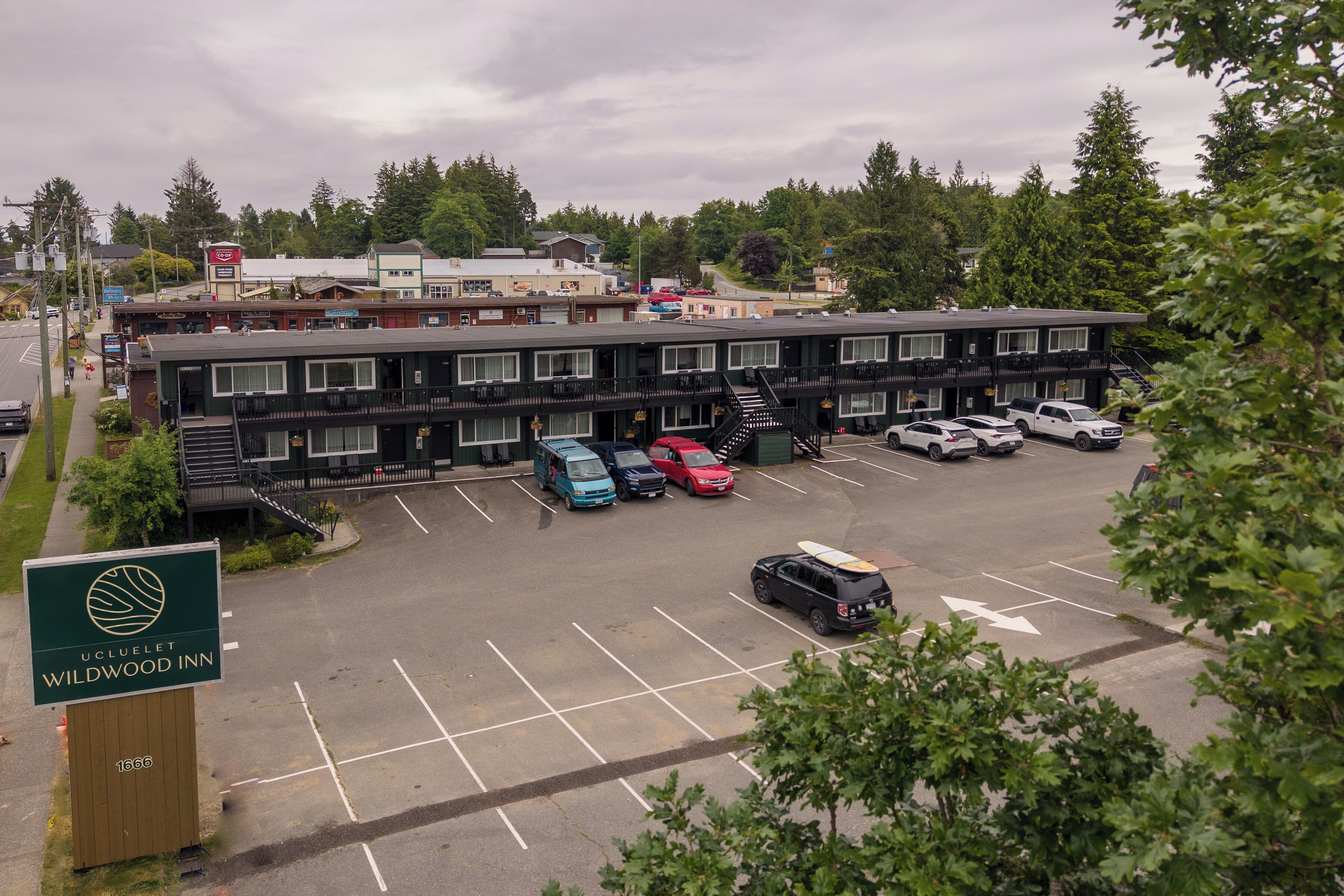A Wildwood Inn with a parking lot, multiple vehicles, and a sign indicating the name and address.