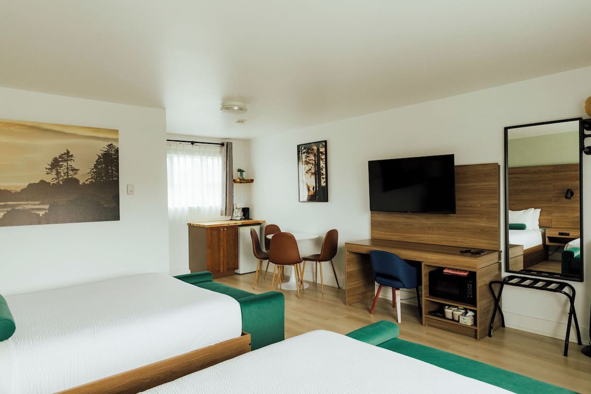 Ein Hotelzimmer mit zwei Betten, einem Schreibtisch, einem Fernseher und einem Spiegel.