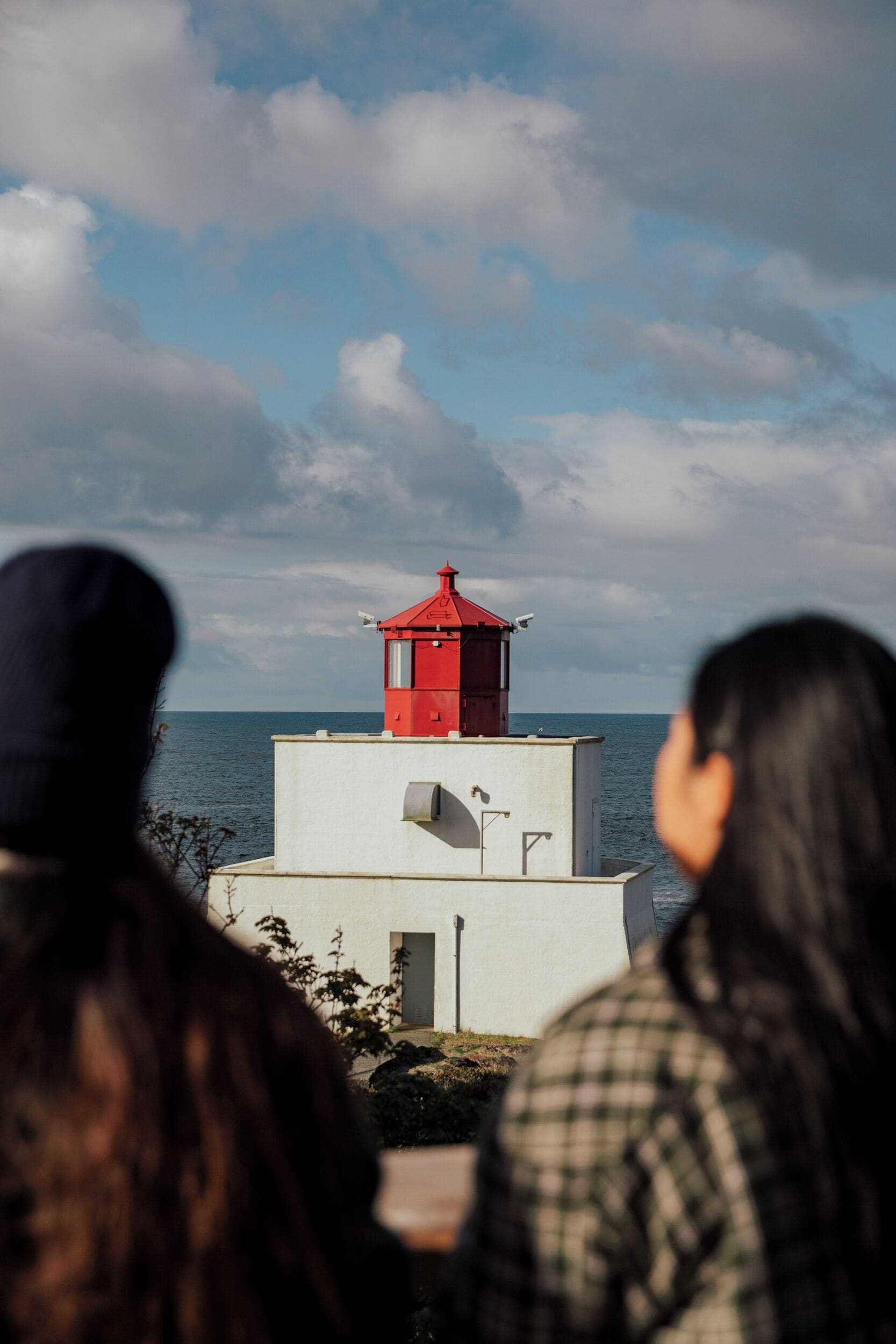A red lighthouse with a white base, overlooking a body of water.