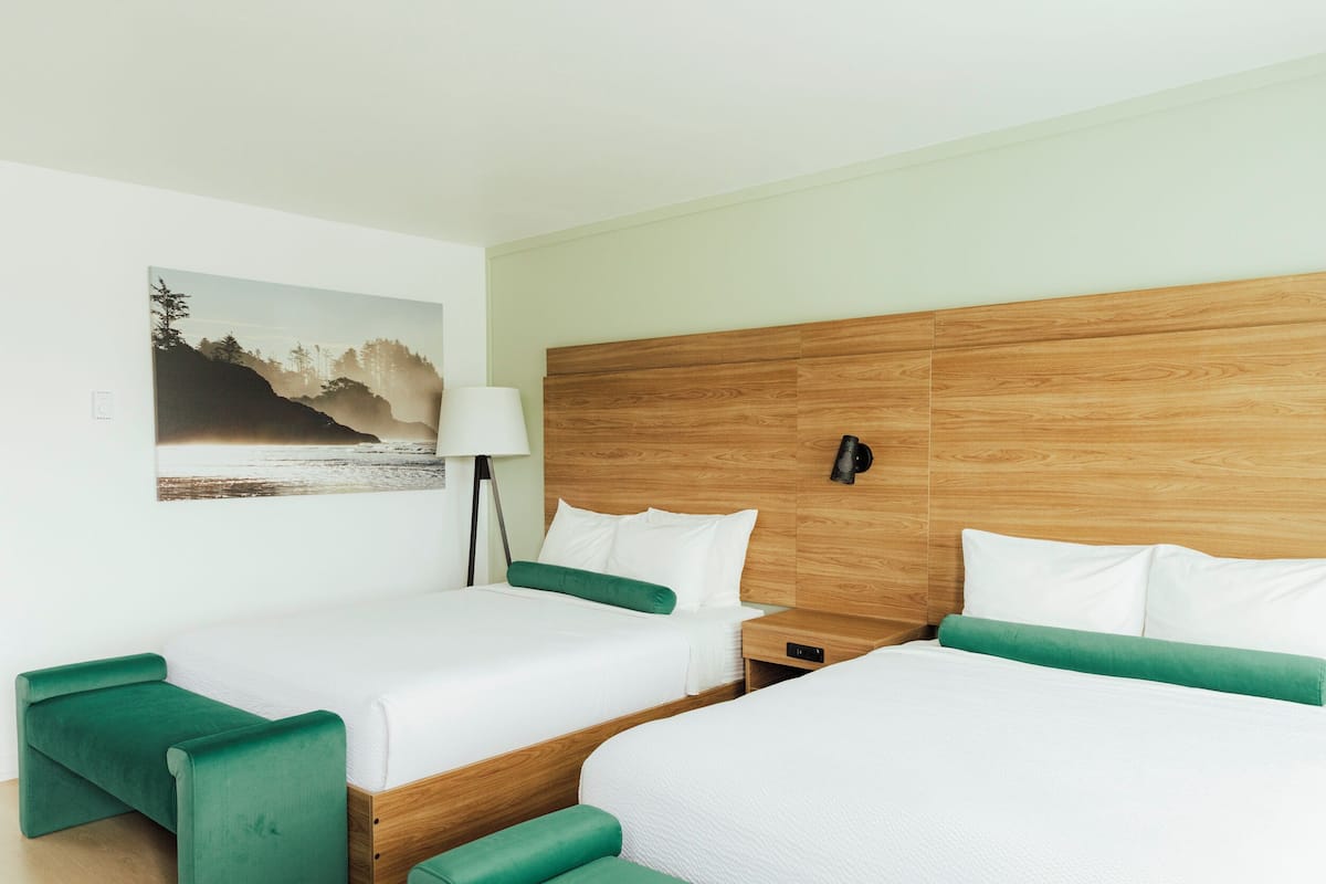 Ein Hotelzimmer mit zwei Betten, einem Nachttisch, einer Lampe und einem Bild an der Wand.