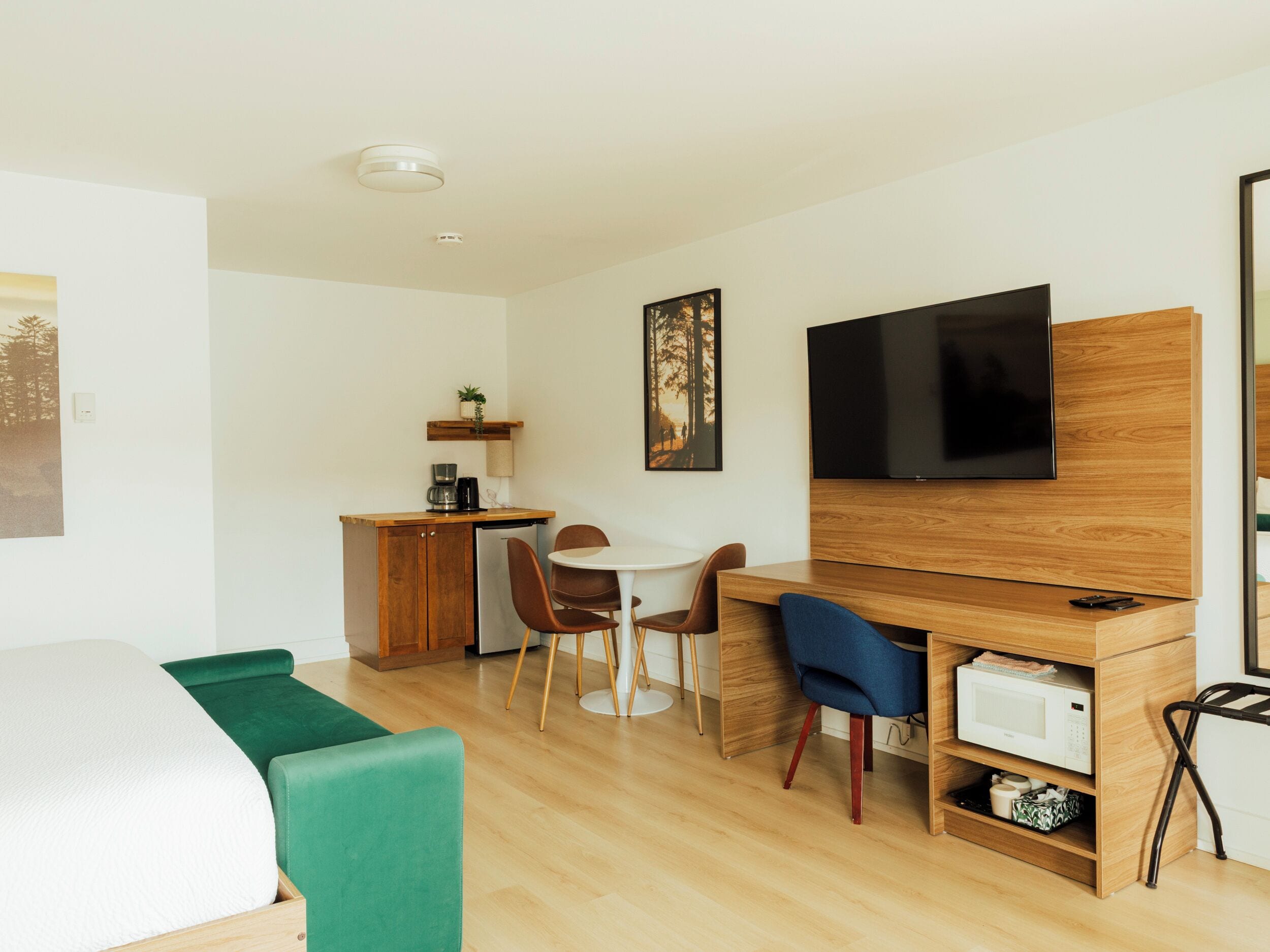 Une chambre moderne et bien éclairée, équipée d’un lit, d’un bureau, d’une chaise, d’une télévision et d’un four à micro-ondes.