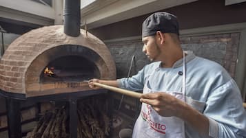Una persona utilizando una herramienta de mango largo para controlar un horno de ladrillo.