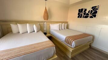 A hotel room with two beds, a hanging light fixture, and wall art.