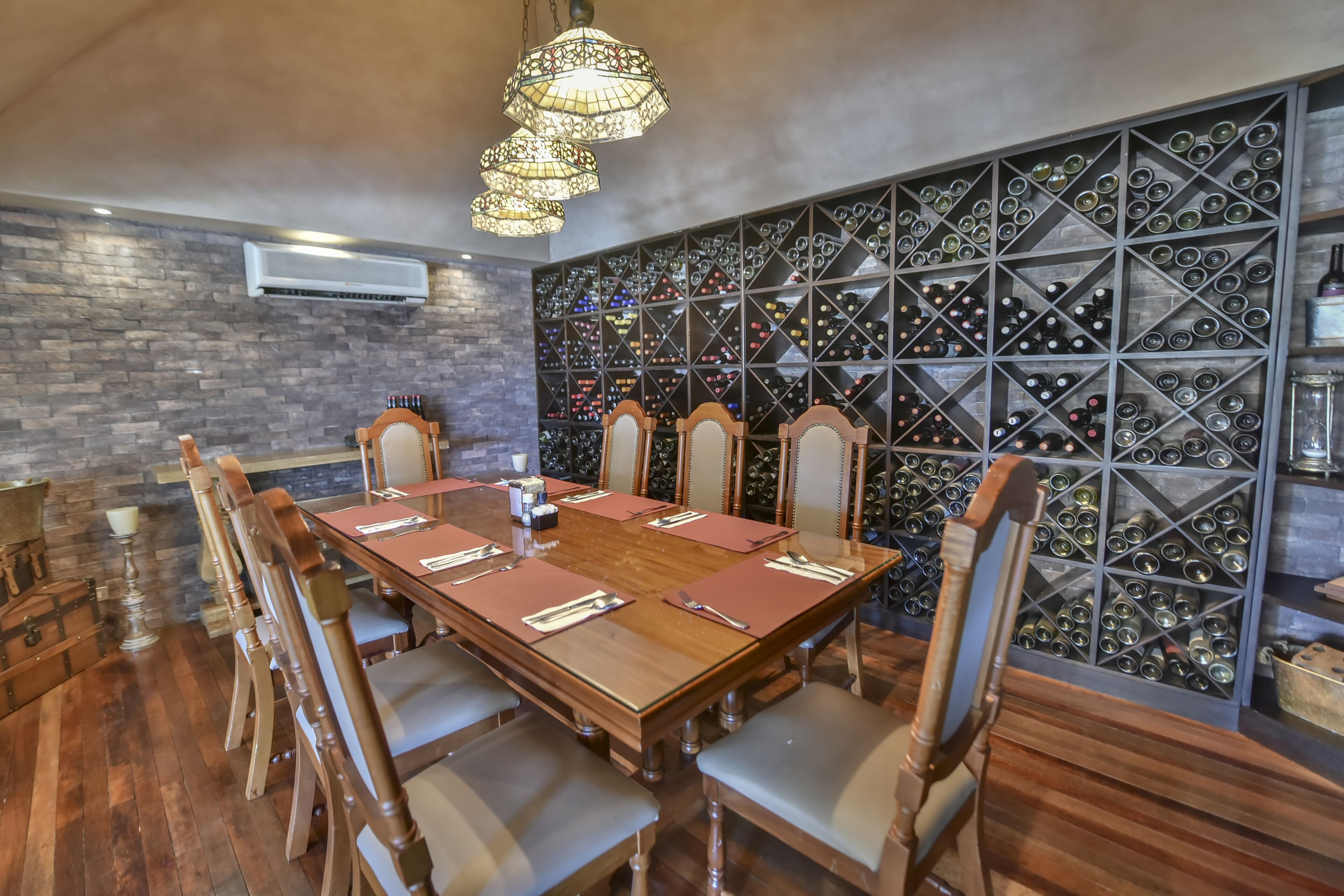 Un coin repas avec une longue table en bois, six chaises et un meuble à vin en arrière-plan.