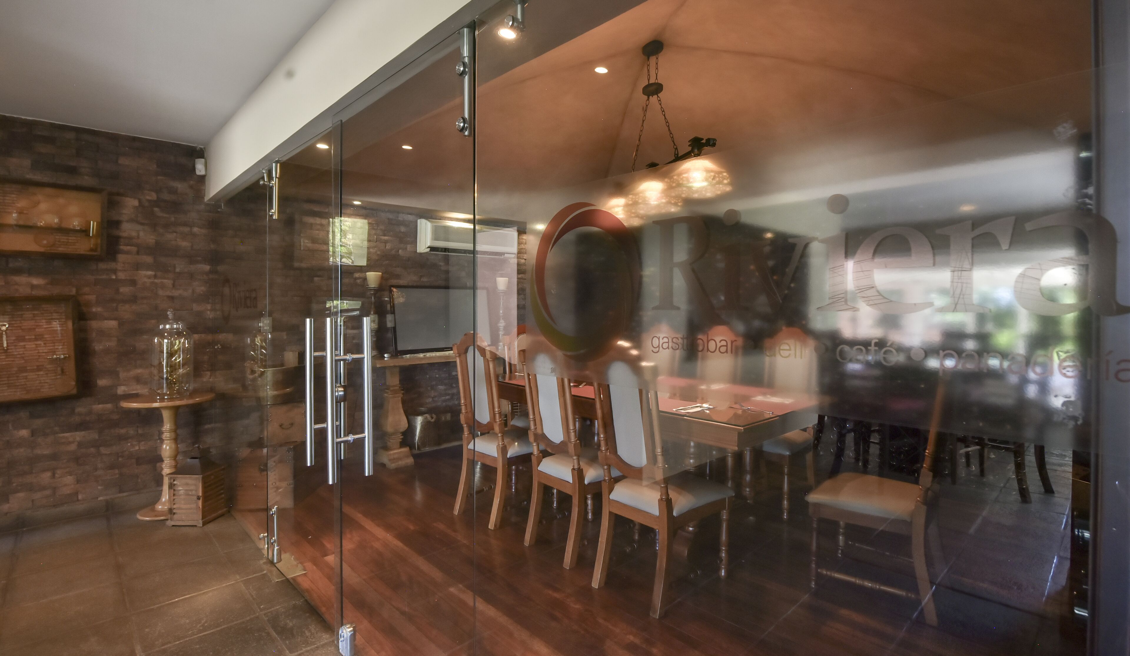 Ein modernes Interieur mit einer Glastrennwand, Holzstühlen und einem Esstisch.