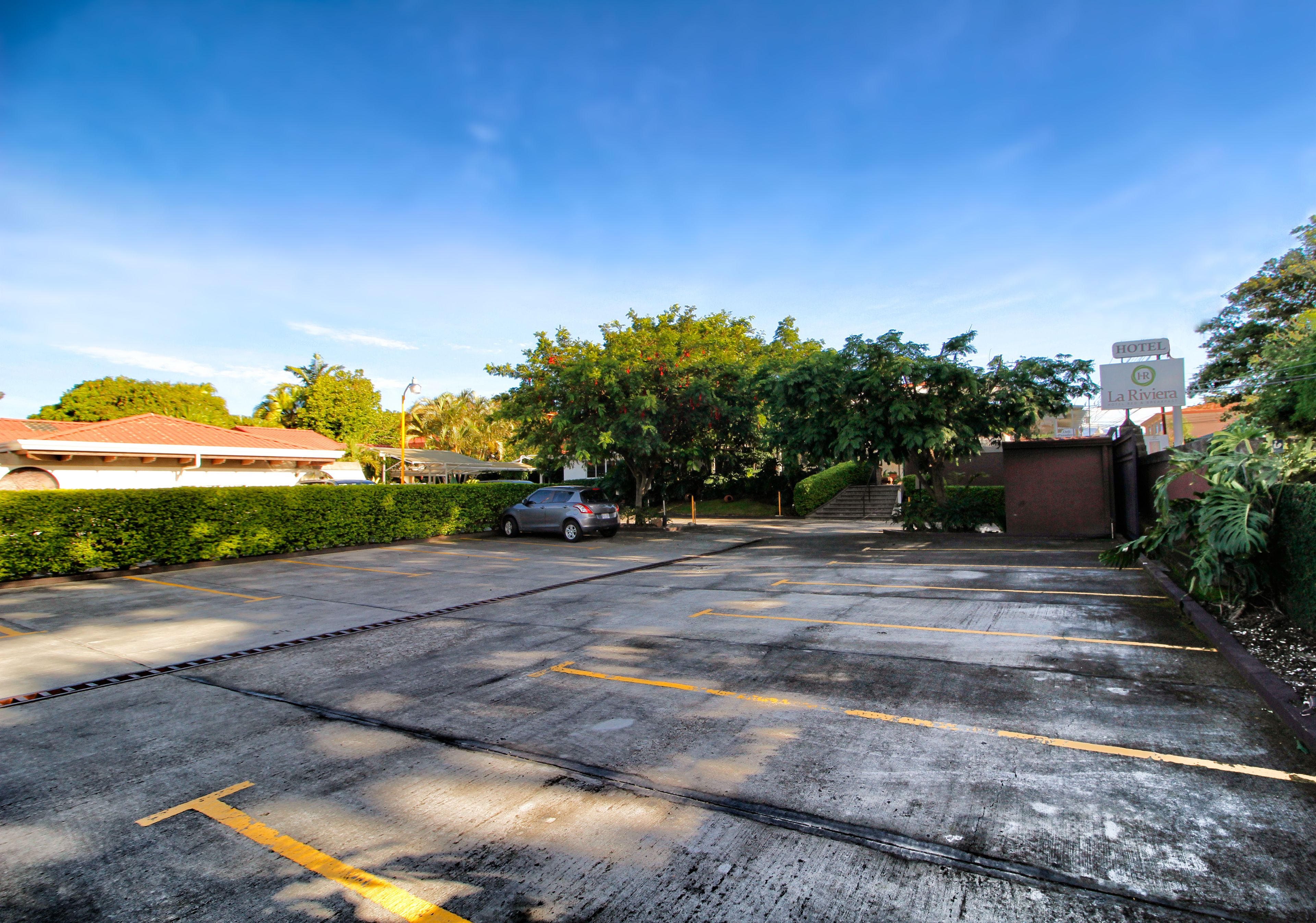 A parking lot with marked spaces, a car, and a hotel sign in the background.
