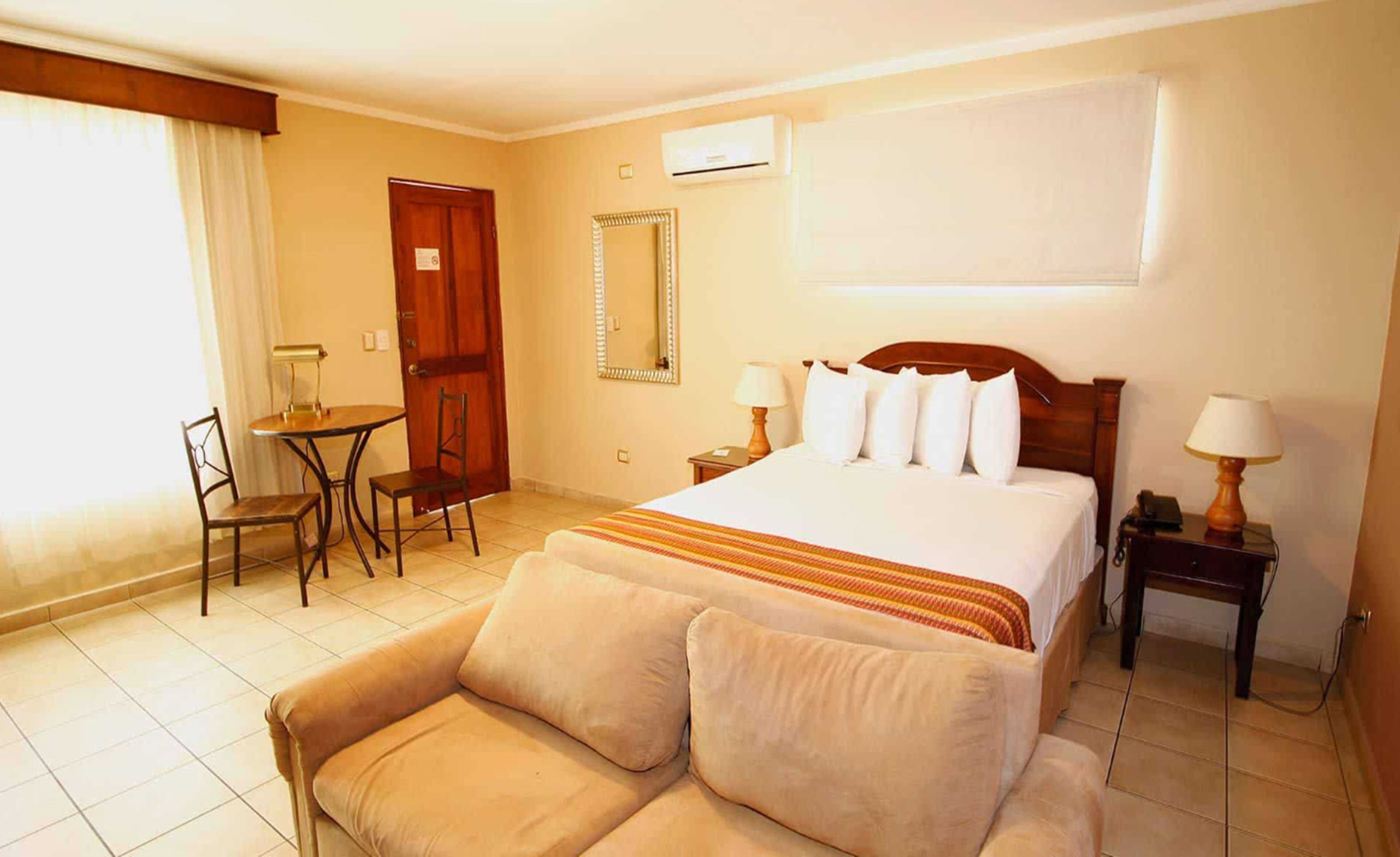 A hotel room with a bed, a sofa, a desk, and a chair.