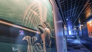 Un intérieur de train moderne, doté d’un design aux lignes courbes, d’un écran numérique et d’un sol à motifs.
