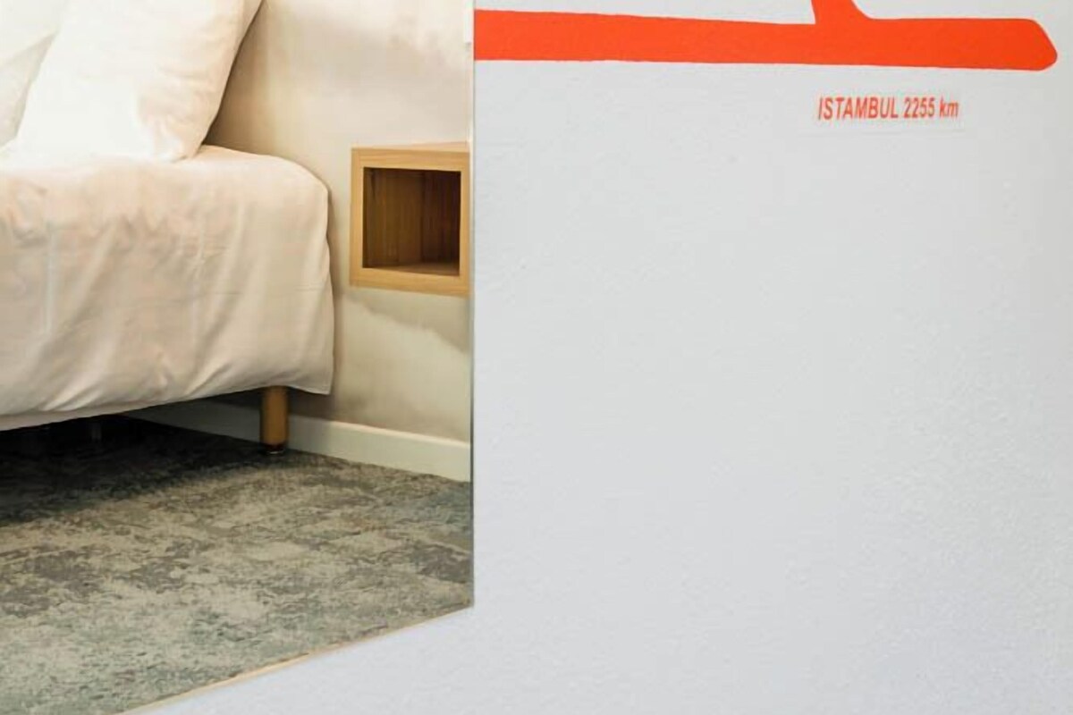 Een slaapkamer met een bed, een nachtkastje en een hanglamp.