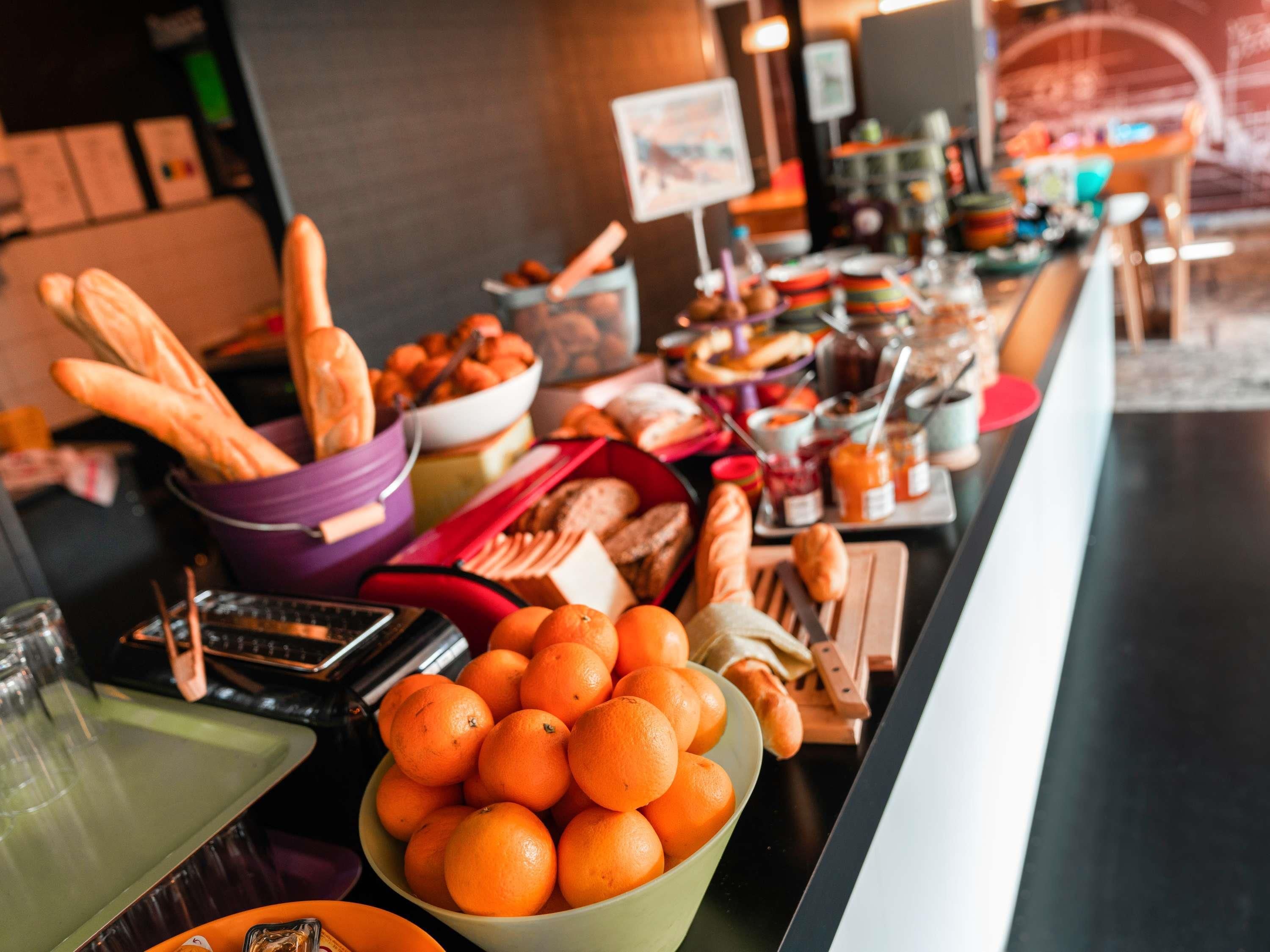 A buffet table with various food items including bread, oranges, and condiments.
