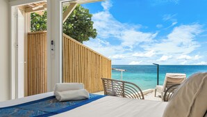 A bedroom with a bed, a chair, and a view of the ocean.