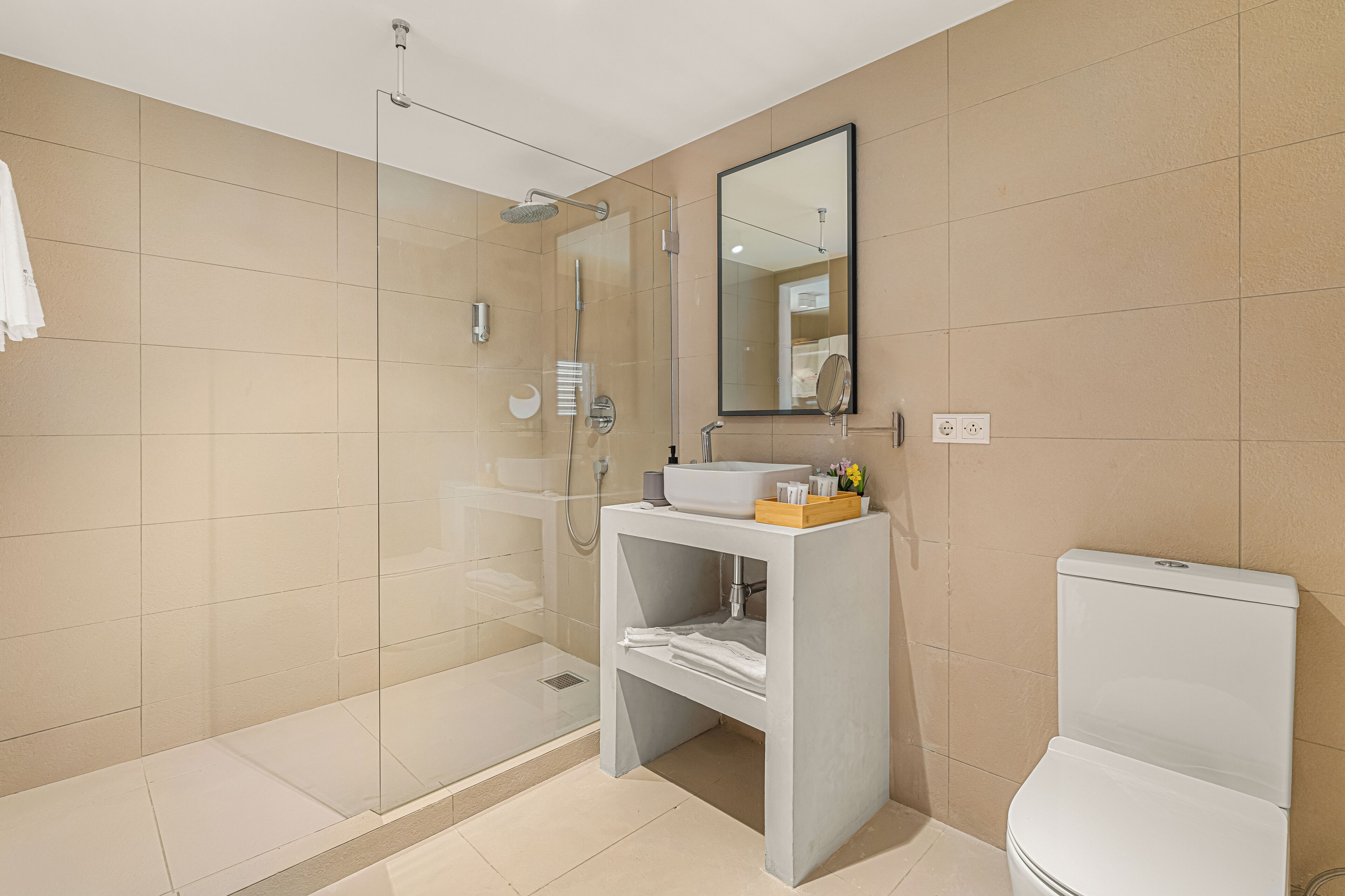 A modern bathroom with a glass-enclosed shower, a white sink, and a toilet.