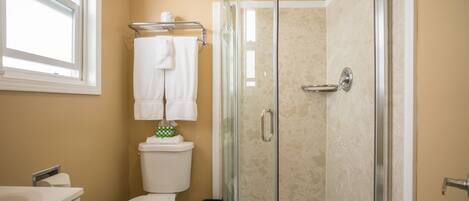 Un baño con inodoro, lavabo y cabina de ducha con mampara de vidrio.