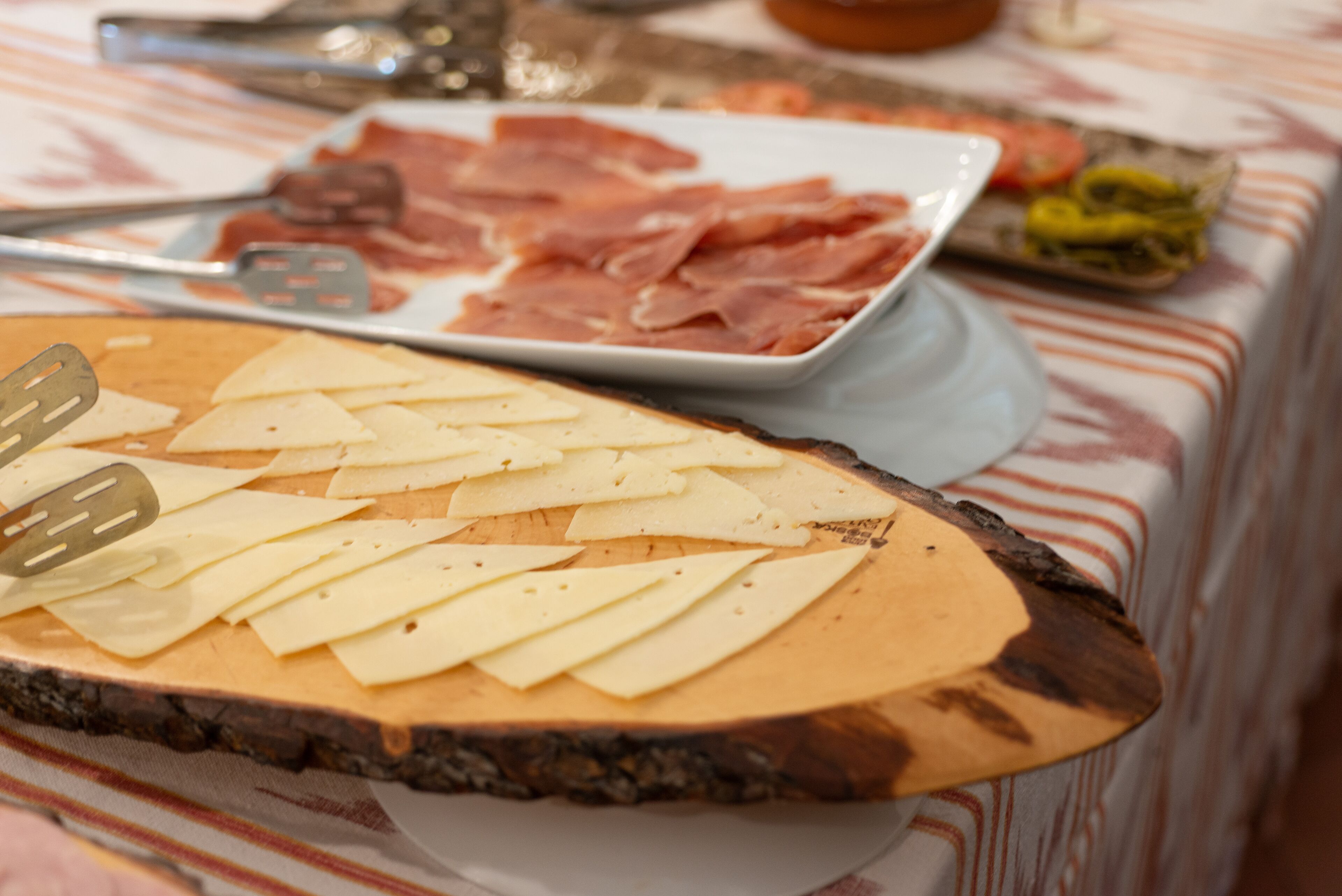 A wooden cutting board with cheese slices and a cheese knife.