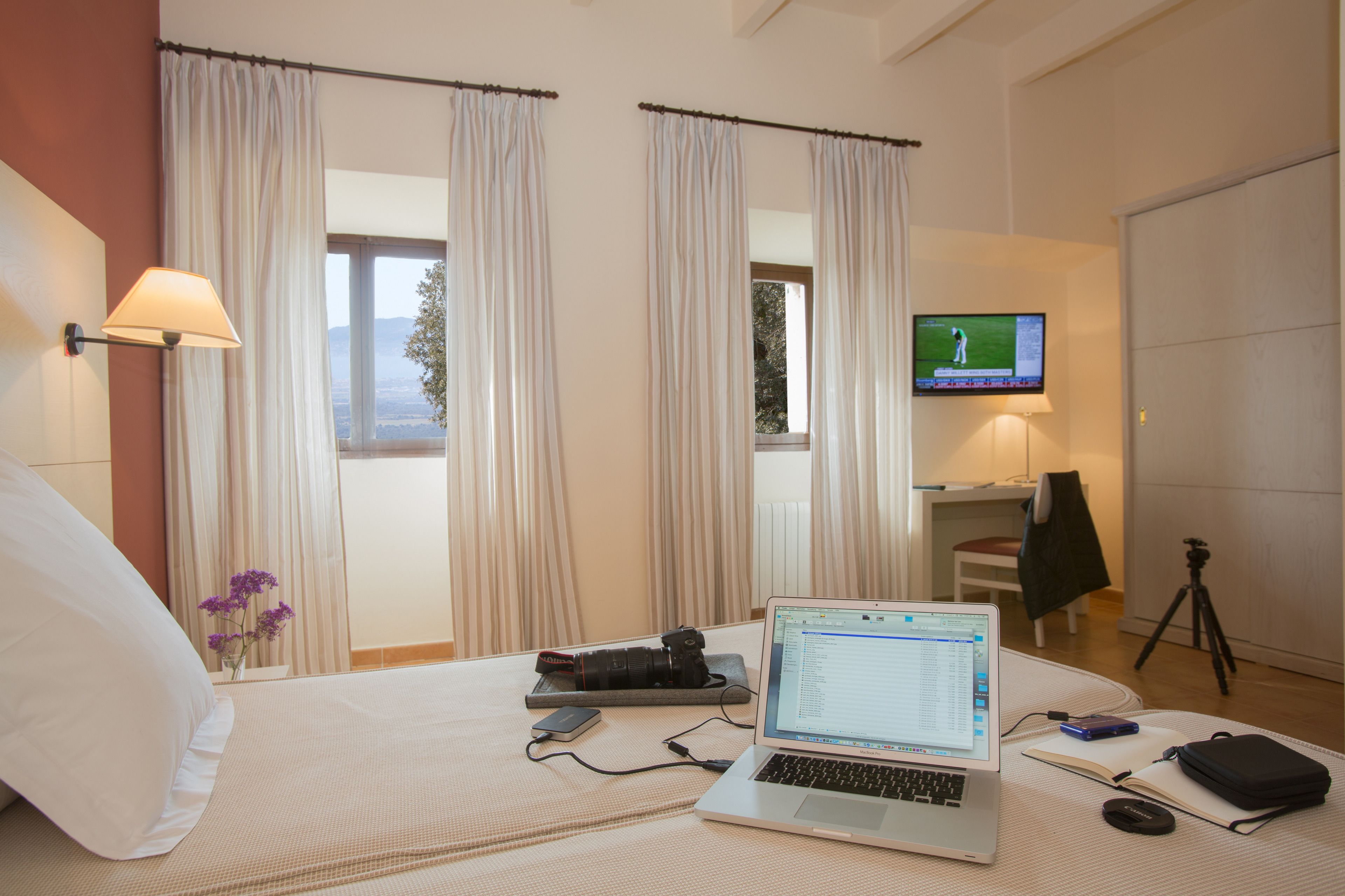 Ett hotellrum med en säng, en bärbar dator, en kamera och ett stativ.
