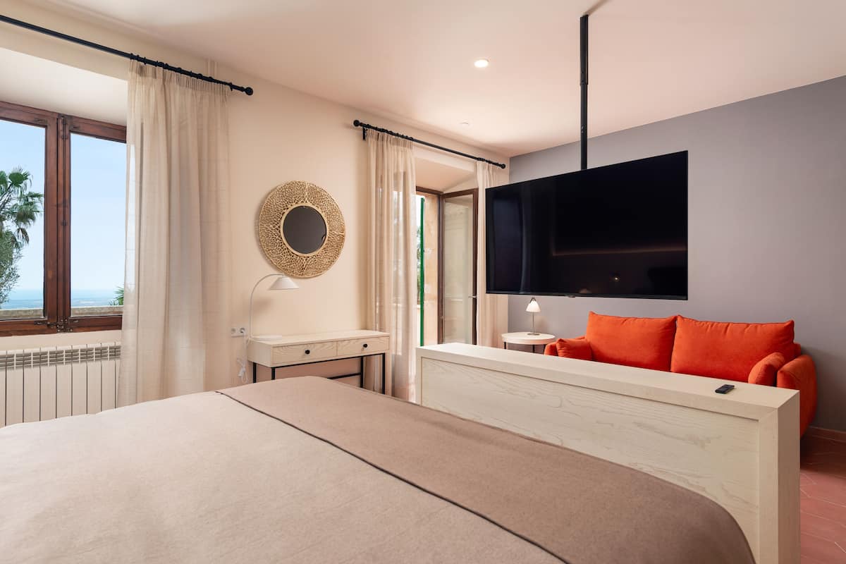 Een moderne hotelkamer met een groot bed, een bureau, een televisie en uitzicht op de omgeving.