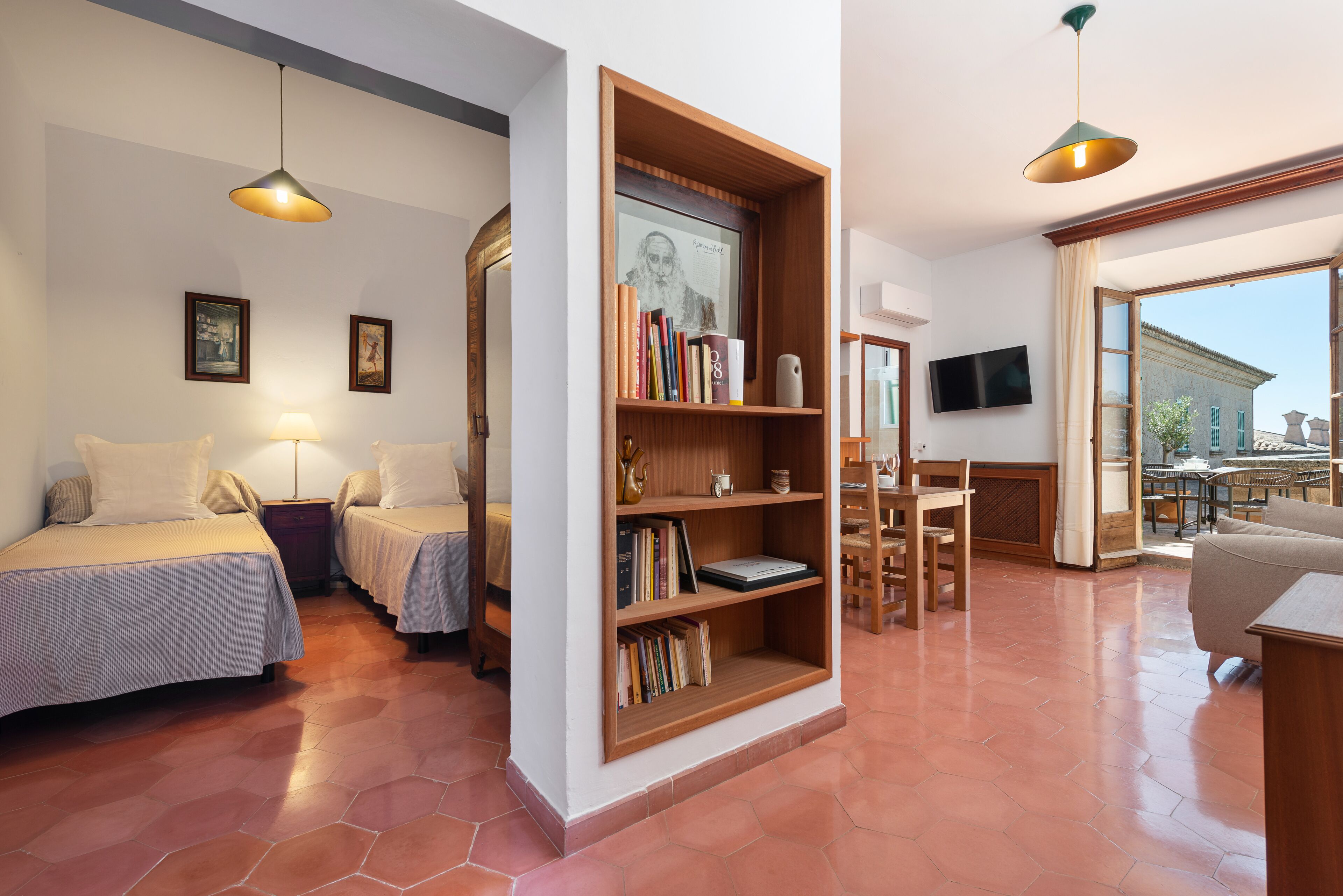 Una habitación acogedora con dos camas, una estantería de madera, un televisor y un ventanal grande.