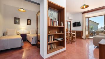 Una habitación acogedora con dos camas, una estantería de madera, un televisor y un ventanal grande.