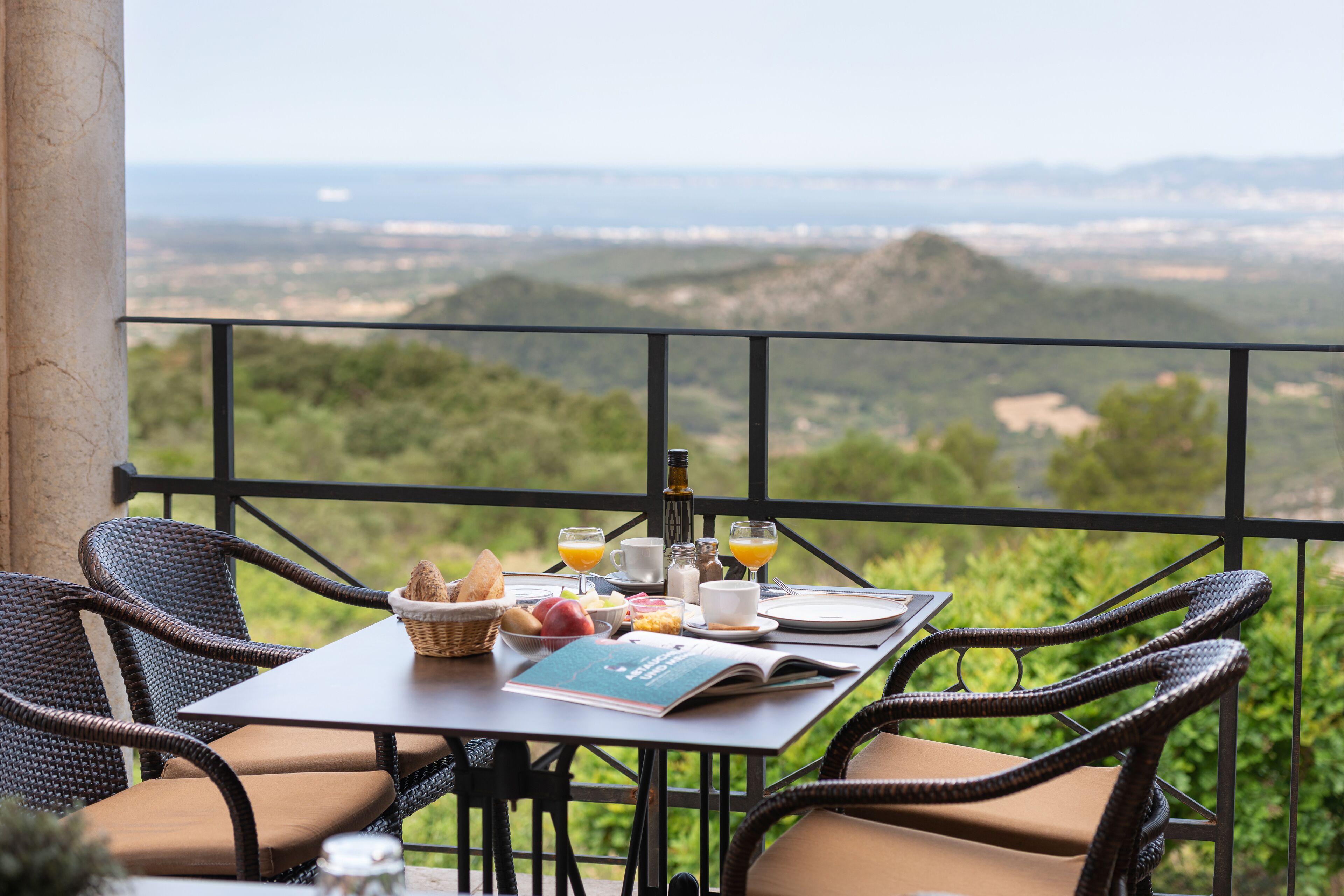 Ein Tisch gedeckt mit Frühstücksgebäck, einem Buch und Blick auf die Landschaft.
