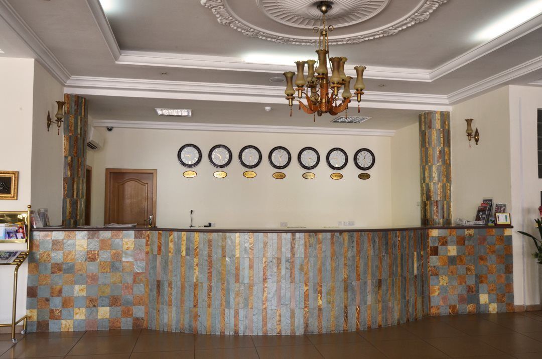 A reception area with a check-in counter, a chandelier, and a wall with multiple clocks.