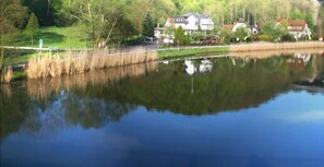A calm lake with a house and trees in the background. - Flux - Biohotel im Werratal (Hann. Muenden)
