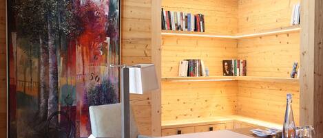 Un interior de madera con un cuadro, estanterías, un escritorio y una lámpara.