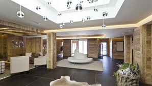 A spacious lobby with a central seating area, wooden accents, and a ceiling with hanging spherical lights. - Hotel de Rougemont & Spa (Rougemont)