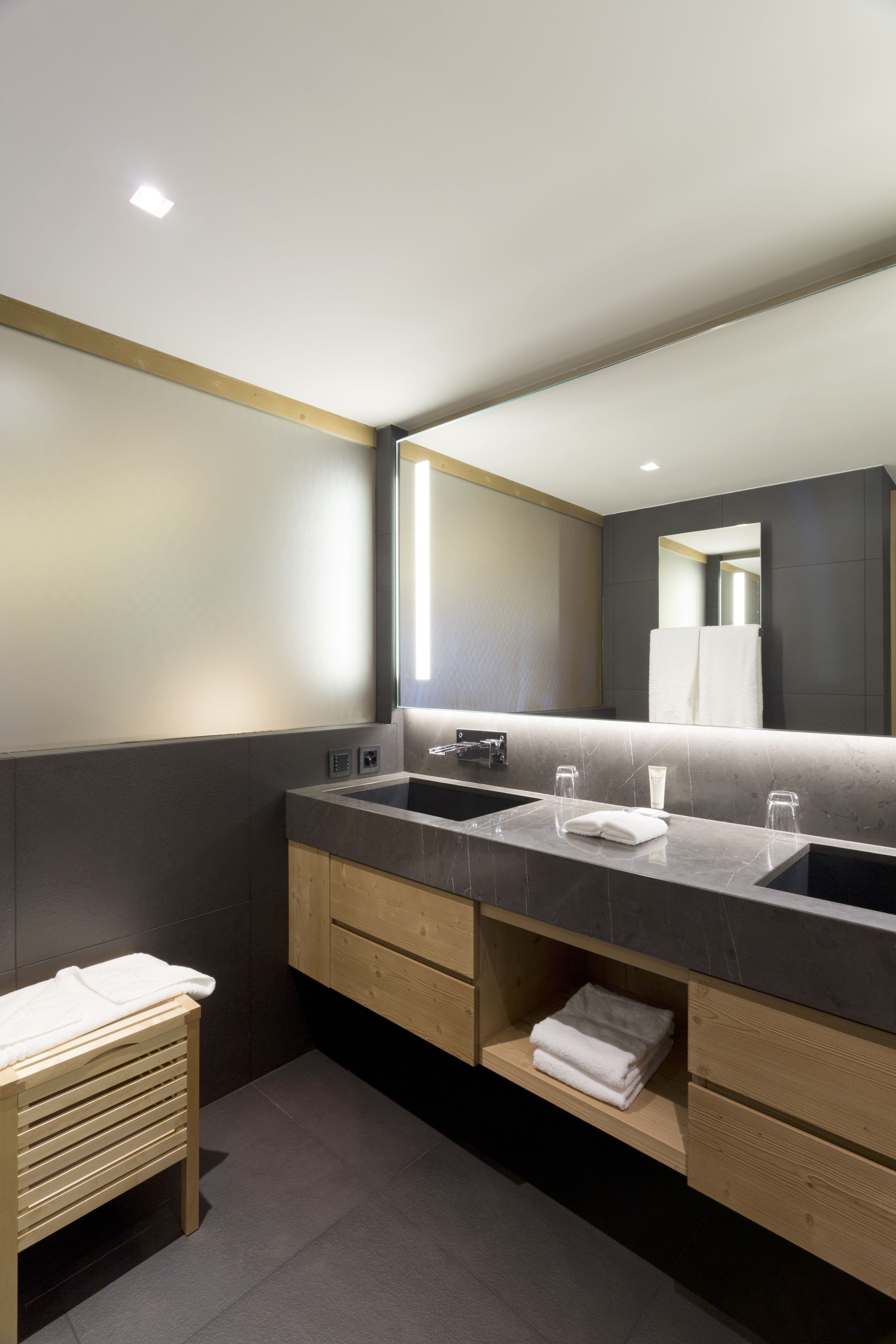 Une salle de bain moderne avec un grand miroir, deux vasques et des meubles en bois.