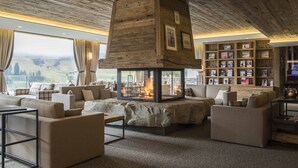 A cozy living room with a fireplace, comfortable seating, and a bookshelf filled with photos. - Hotel de Rougemont & Spa (Rougemont)