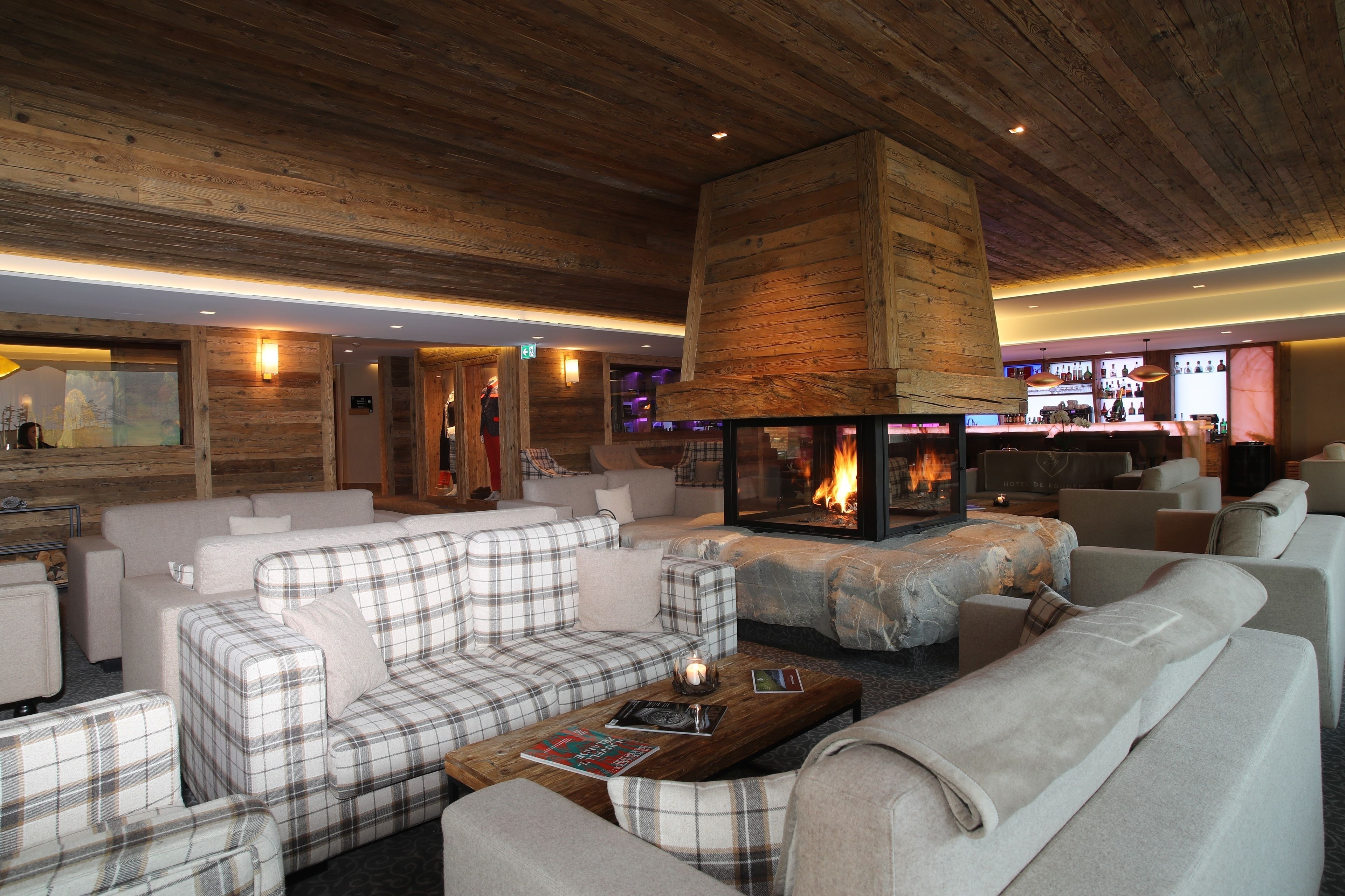 Un rincón acogedor con chimenea, asientos cómodos y un bar al fondo.